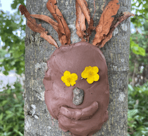 close‑up of expressive outdoor forest face art with leaves and bark