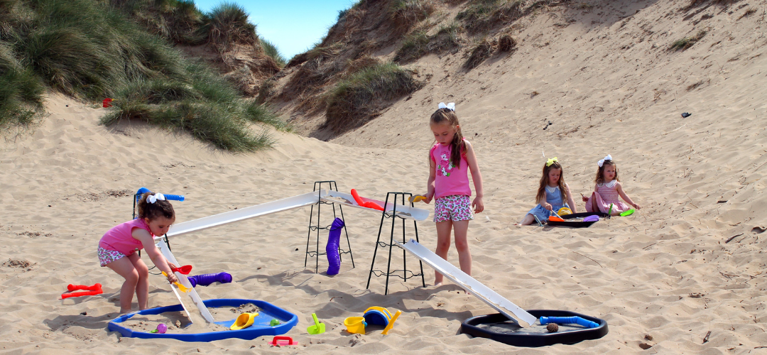 children playing with water chanelling equipment in sandy terrain