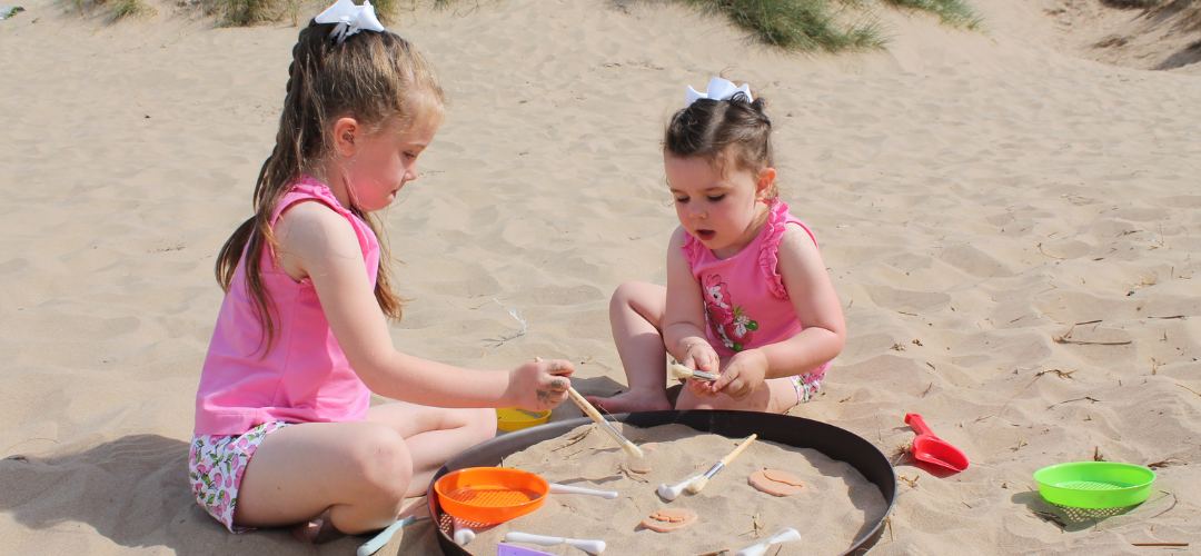 two children playing with sand and tuff tray