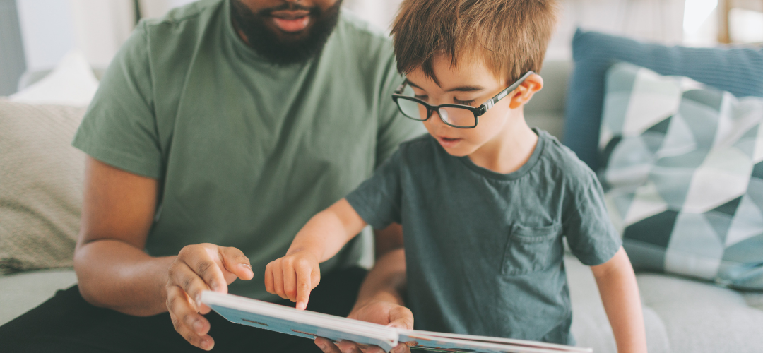 child wearing glasses and reading with parent
