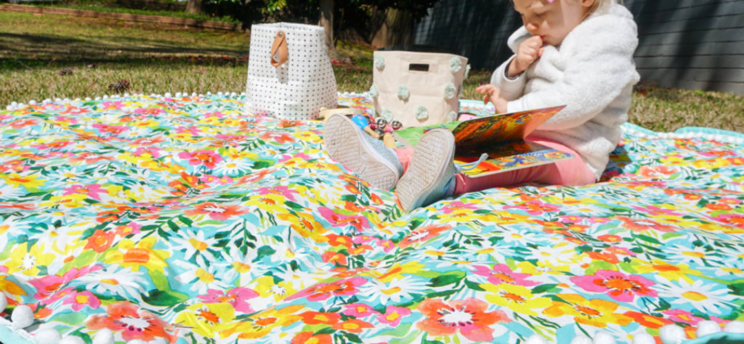 child sat on a picnic mat outdoors