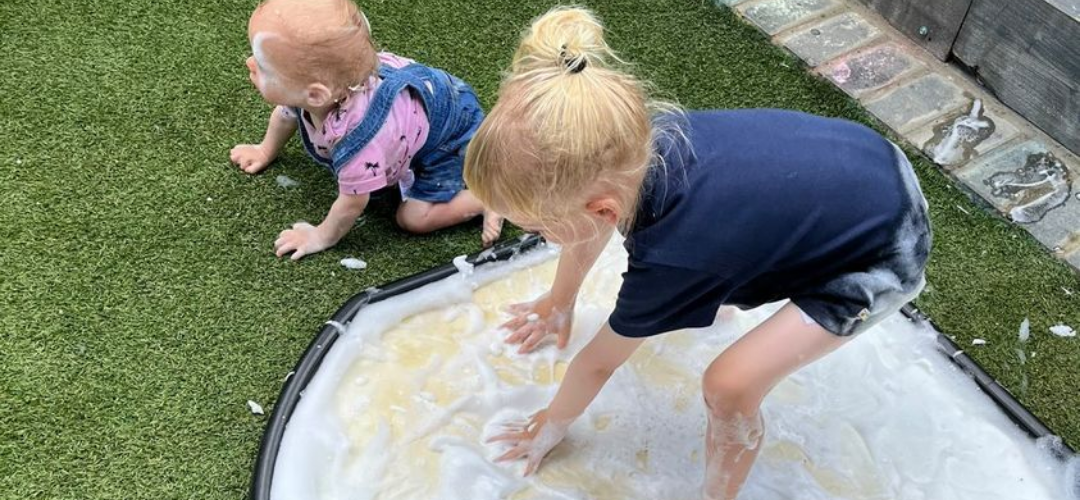 child stood on a sponge mat with soap foam everywhere