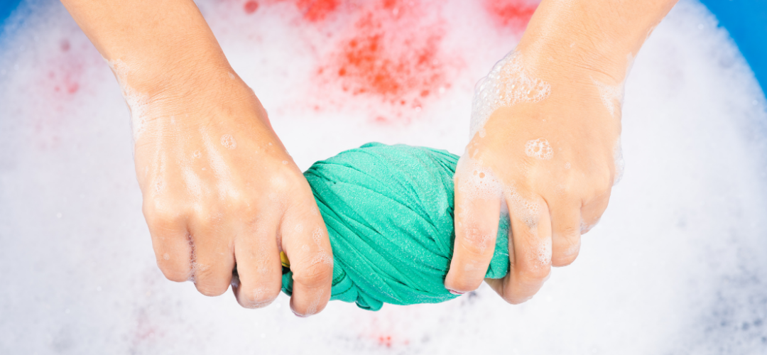 child wringing out a cloth from soapy water