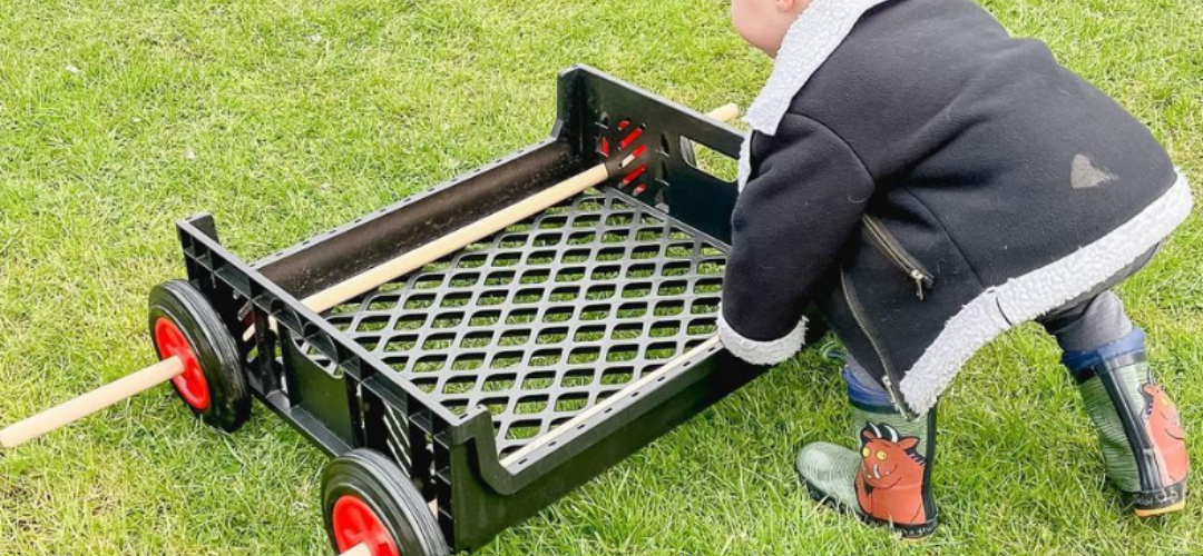 child pushing a makeshift car made from crates and tyres