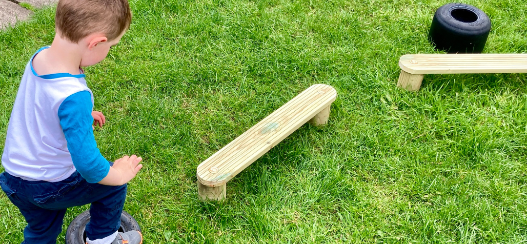 child navigating an obstacle course of tyres and planks