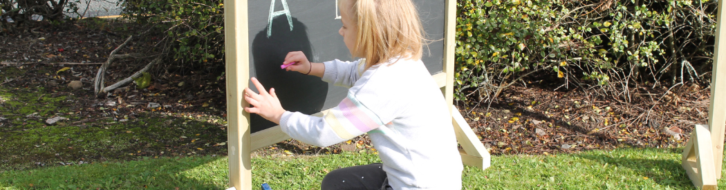 child forming letters on black board