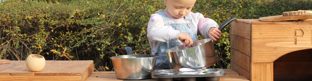 child playing with outdoor mud kitchen equipment