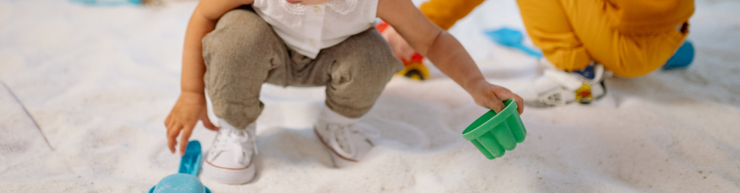 child holding sand mold over sand pit