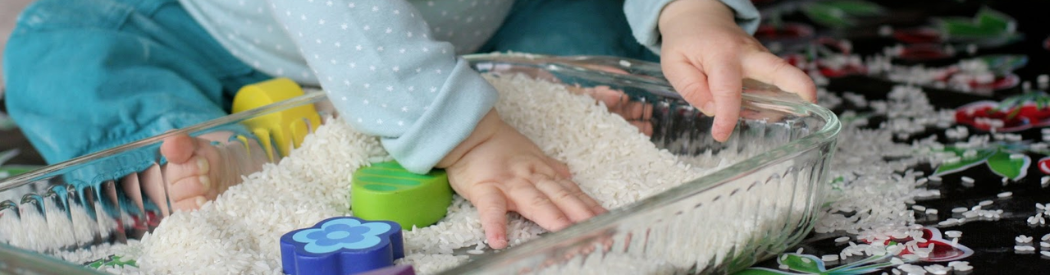 baby reaching into a sensory tray