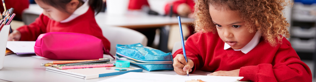children in school uniform writing at their desks