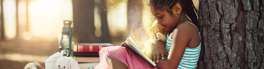 child reading book against tree