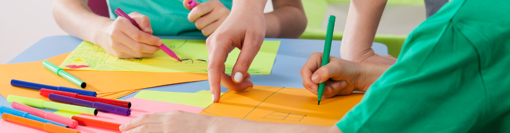 child drawing with coloured pens on coloured paper