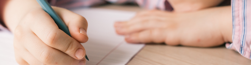 child writing story on piece of paper