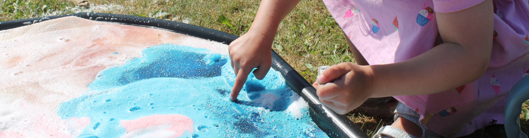 child engaging in water play in tuff tray