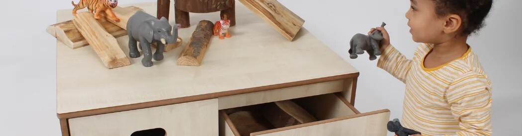 wooden storage table with toys being played with on top
