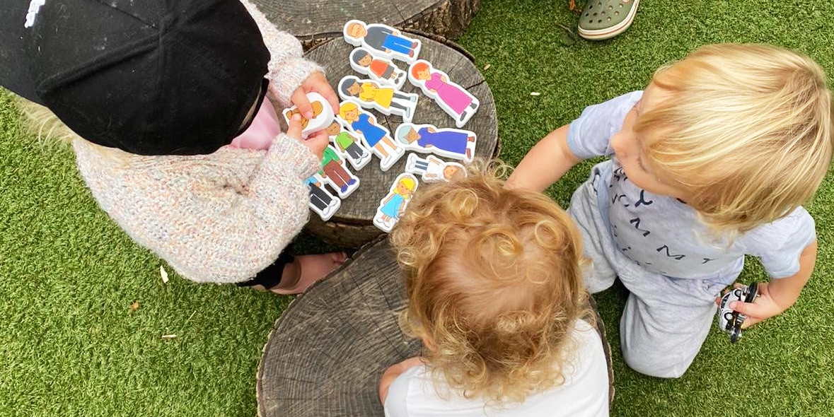 children playing with wooden figures on tree stumps