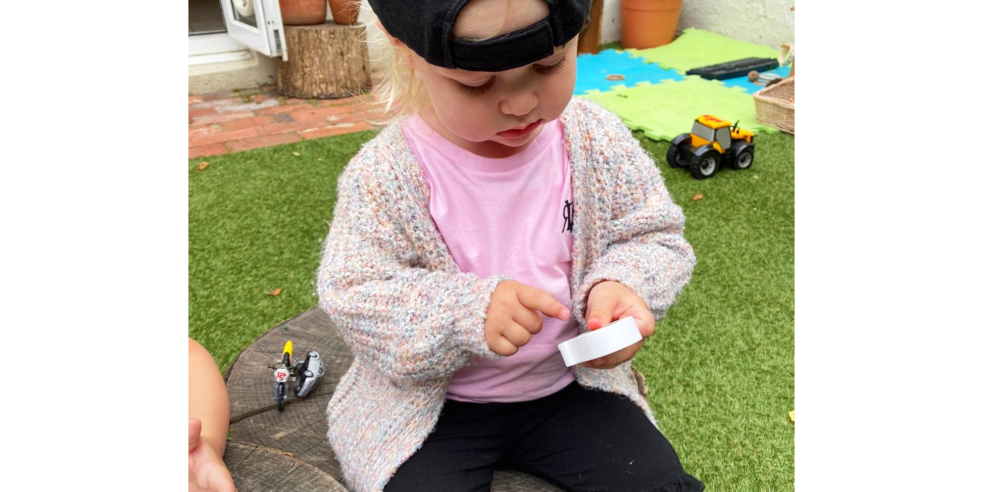 child investigating wooden figures in outdoor play area