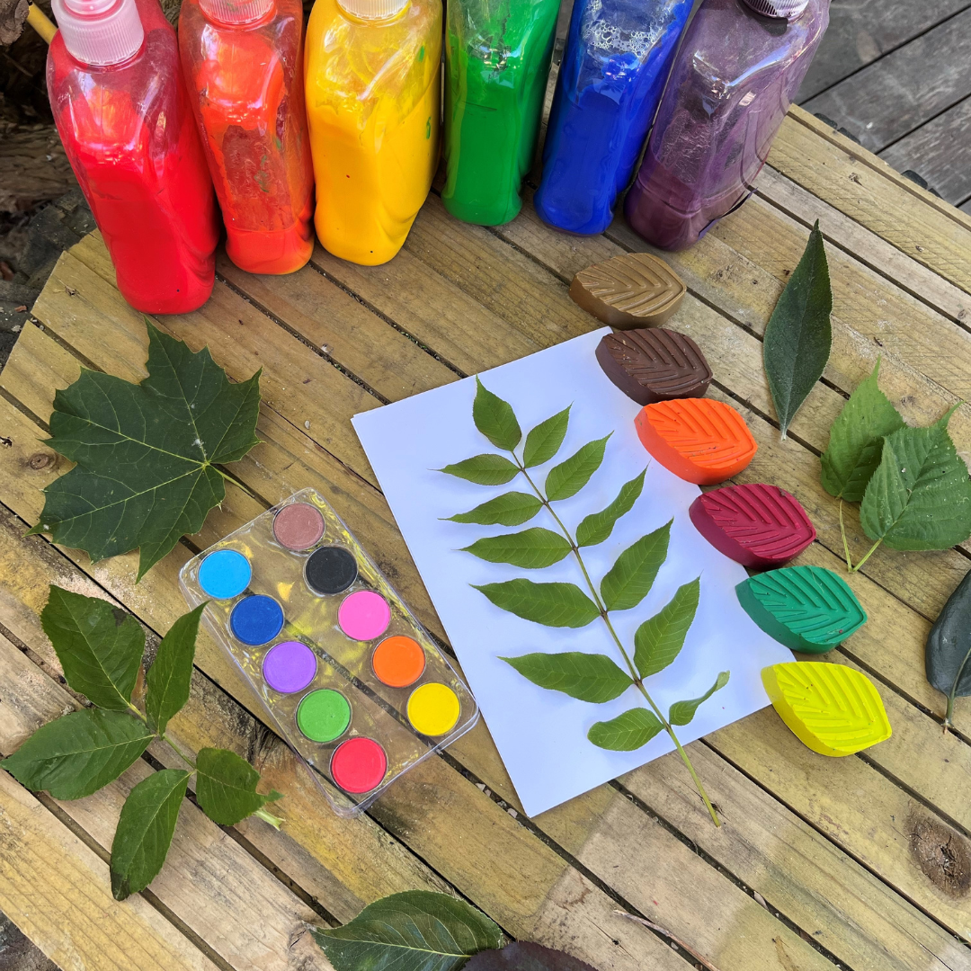 selection of paints, leaves and paper