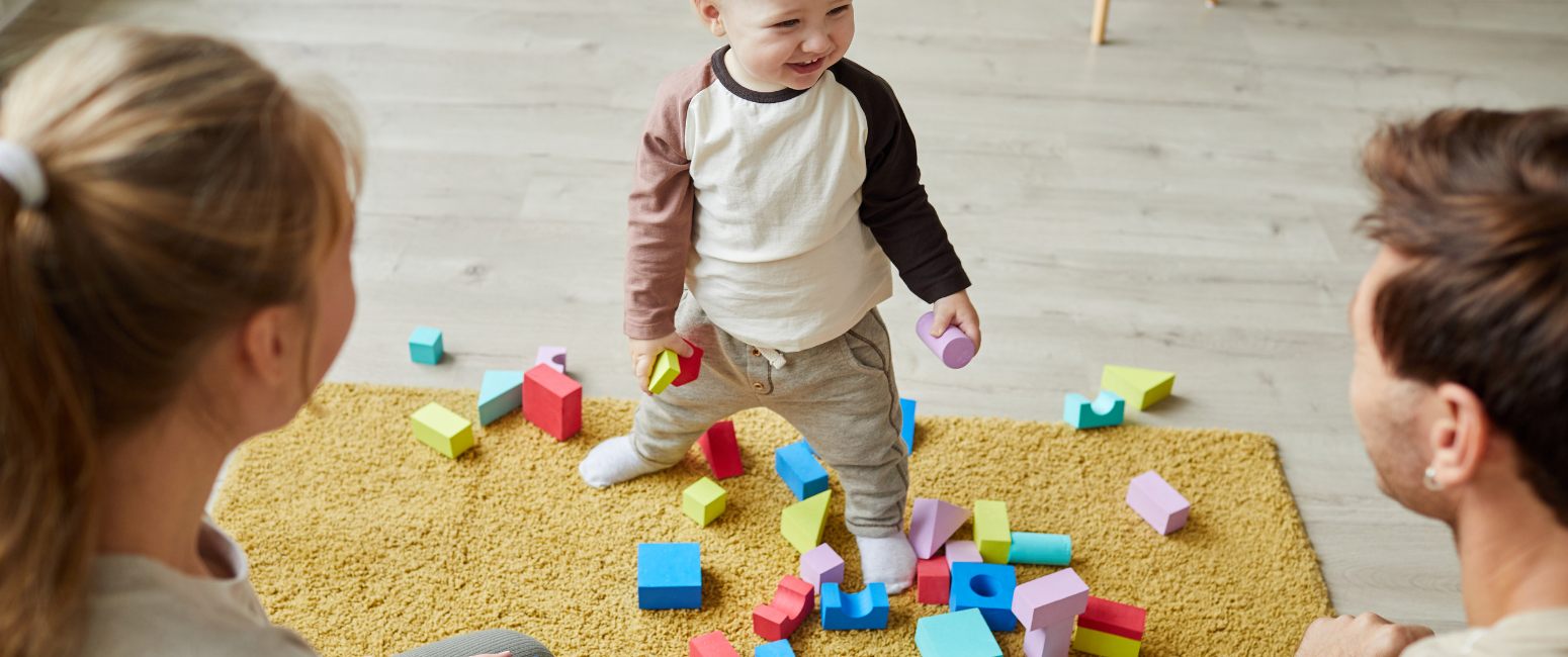 child playing with wooden blocks on yellow carpet