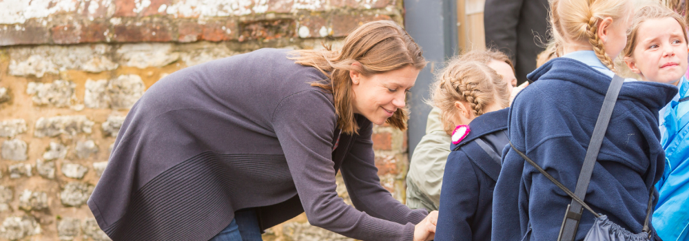 teacher helping child put on coat
