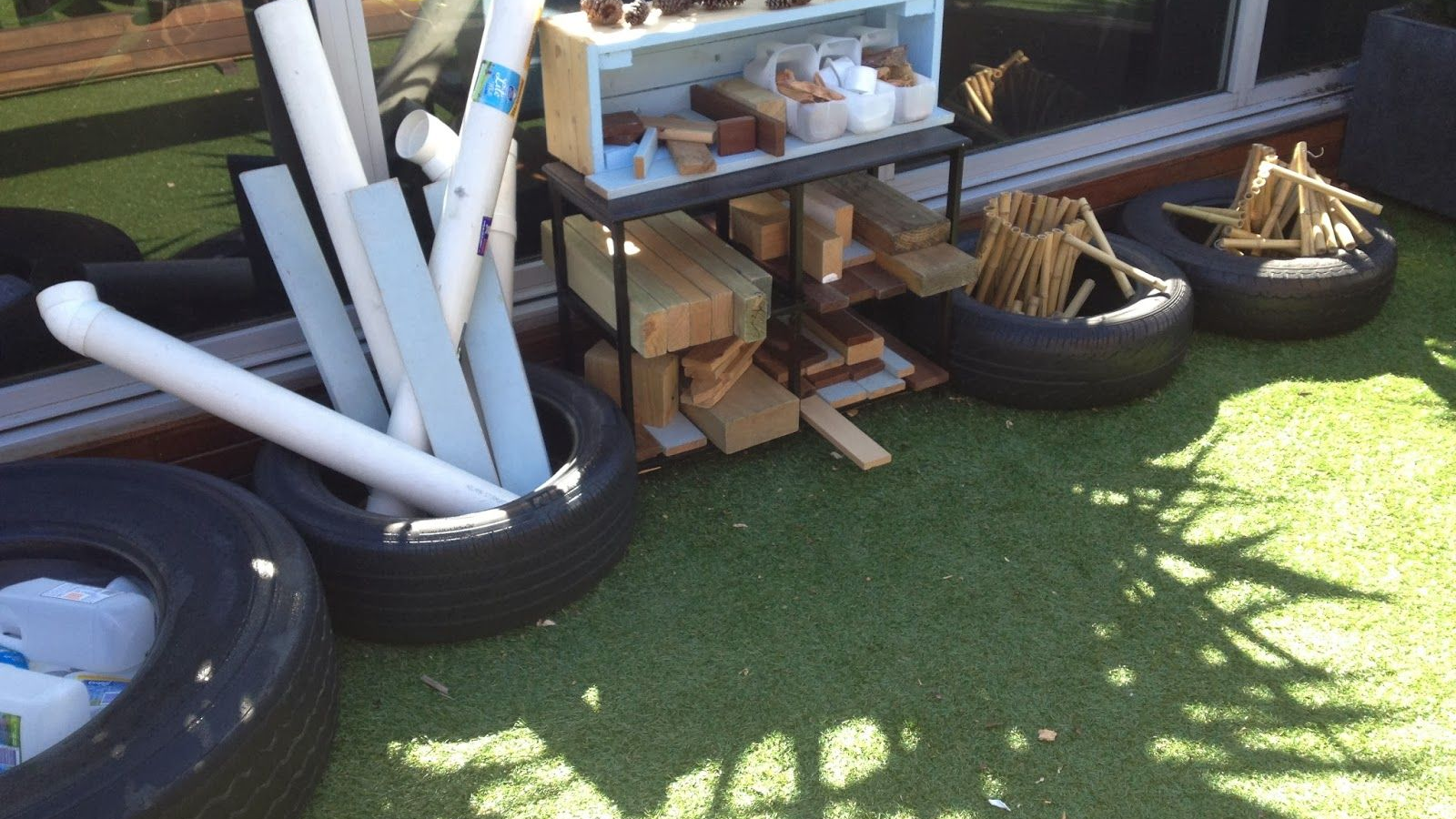 tyres on the ground holding an array of materials including guttering, milk bottles and bamboo pieces